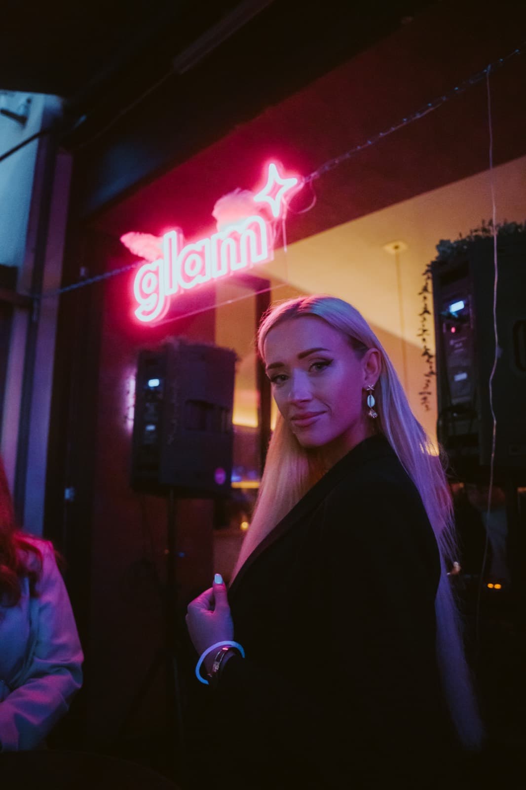 Guest in front of the glowing glam neon sign at night
